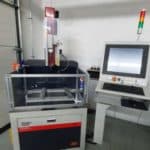 Industrial CNC machine with monitor and control panel in a workshop setting.