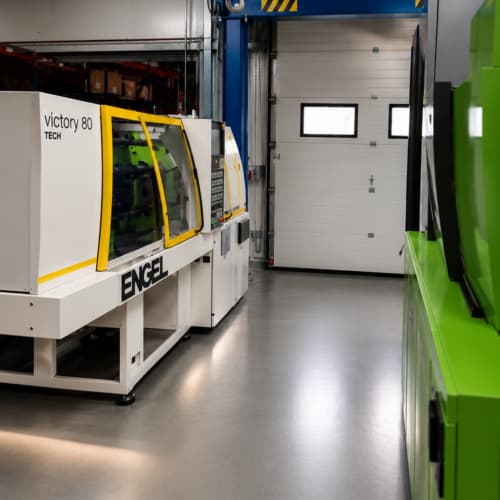 Spritzgussmaschine im Industriewerk mit moderner Technik und blauer Hebevorrichtung.