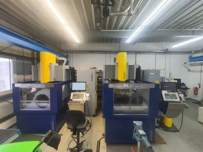 Two advanced OPS Ingersoll CNC machines in an industrial workshop with control panels and bright overhead lighting.
