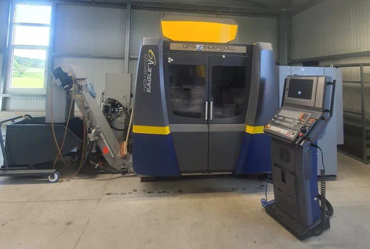 High-tech CNC machine in industrial workshop setting, featuring control panel and safety enclosure.