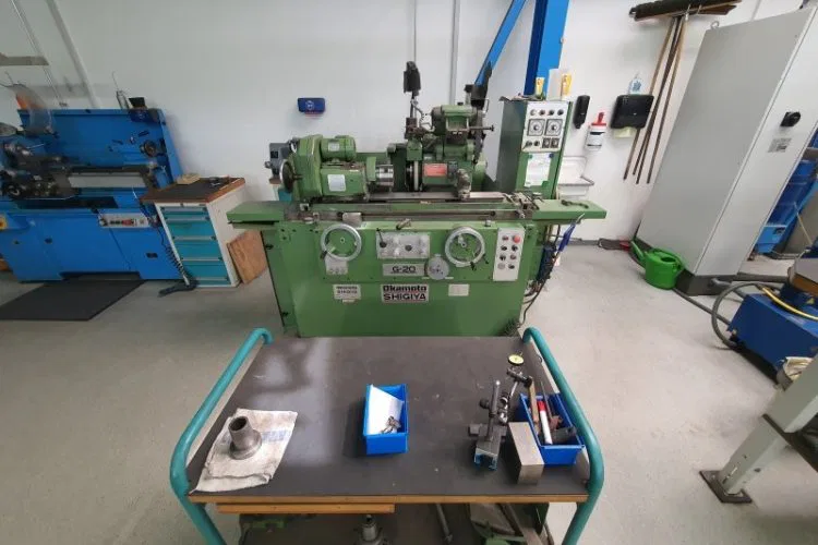 A green industrial lathe in a workshop with tools on a cart, emphasizing precision engineering and machinery.